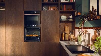 Moderna cucina con caldi mobili in legno, forno incorporato con cibo all'interno e un elegante lavello