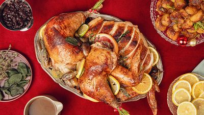 Carved up lemon and thyme roast turkey with golden skin on a serving platter in a festive christmas setting.