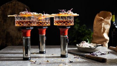 Tre cocktail raffinati con guarnizioni su tavolo scuro. 