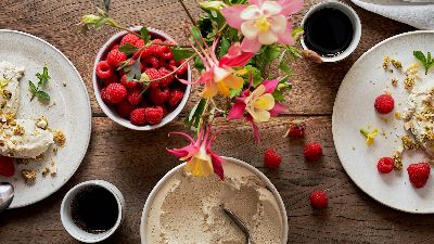 Piatti di dolci con panna, lamponi e pistacchi. 