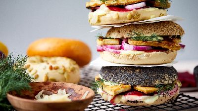 Tre burger gourmet impilati con condimenti vari. 