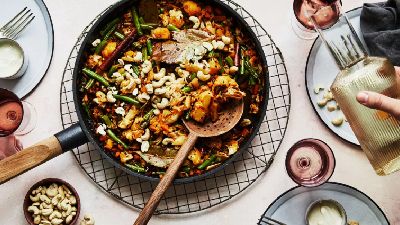 Versando una bevanda accanto a riso colorato in padella. 