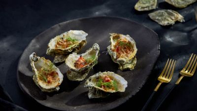Ostriche grigliate con erbe su piatto nero. 