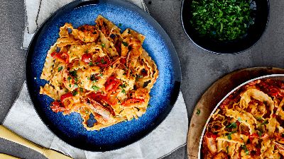 Pasta con gamberi ed erbe su piatto blu. 