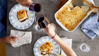 Brindisi con vino rosso su lasagna e teglia fumante. 