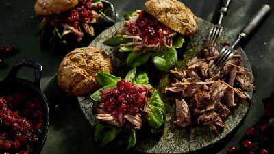 Tavola rustica con carne sfilacciata, verdure e panini. 