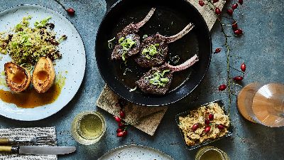 Costolette d'agnello con verdure arrosto su tavola rustica. 