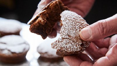 Mano con dolce al cioccolato spolverato di zucchero. 