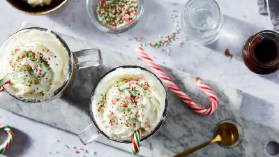 Due tazze festive di panna montata guarnite con granelli colorati