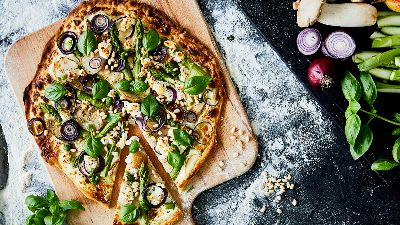 Pizza con olive, erbe e verdure su tagliere. 