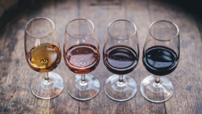 Fila di bicchieri di vino di differenti colori su un tavolo di legno