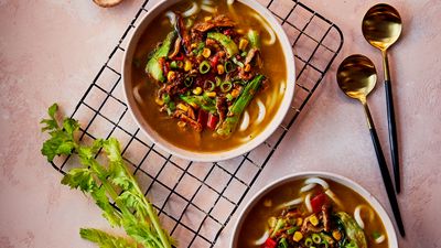 Bowl of vegan ramen with noodles, mushrooms, tofu, and fresh vegetables in broth.     