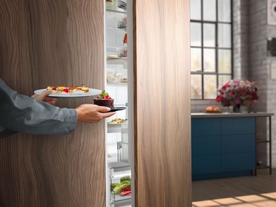 Een close-up van een hand die een takje rozemarijn uit de koelkastlade haalt