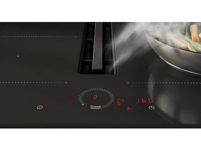 Een slanke zwarte inductiekookplaat met een pan groenten en een digitaal bedieningspanee 