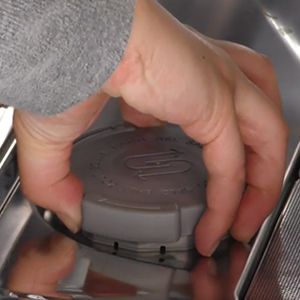 Mano che svita il tappo del serbatoio del sale all&rsquo;interno della lavastoviglie 