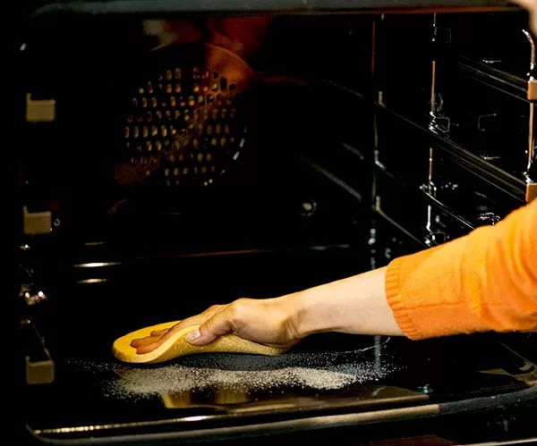Person wiping down inside of oven