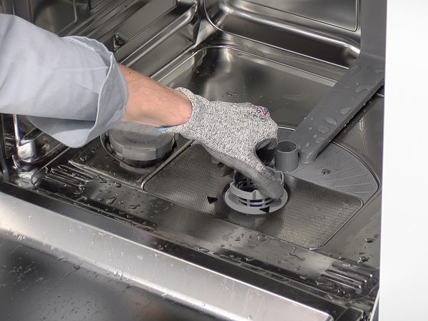 Déverrouillez l'unité de filtrage située au bas du lave-vaisselle et sortez-la délicatement.