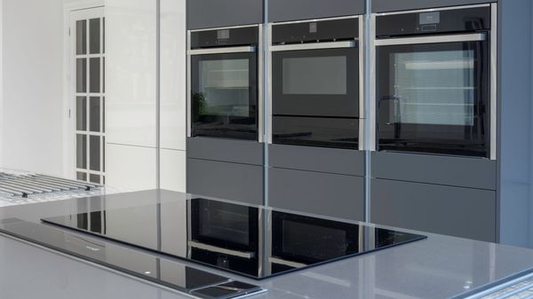 Sleek induction hob on kitchen island surrounded by built-in ovens