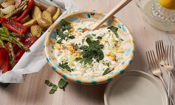 Ciotola di salsa allo yogurt con cetriolo, uova e menta, servita con verdure arrosto e patate