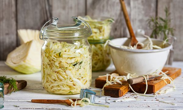 Barattolo di crauti fermentati su tavolo, con cavolo, spezie e utensili da cucina accanto