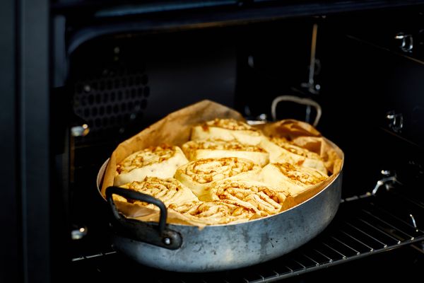 Cinnamon rolls cooking in baking dish in oven