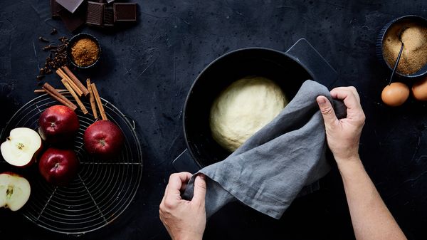 Person putting a ball of dough resting in bowl