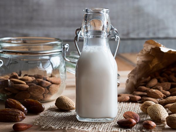 Bottiglia in vetro di latte vegetale su un tavolo con frutta secca