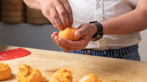 Person shaping dough into little rounds