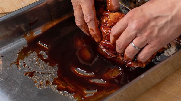 Person massaging marinade over meat