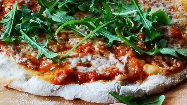 Frisch gebackene Pizza mit K&auml;se und Rucola