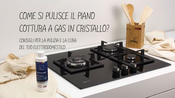 Piano cottura a gas moderno con tre fornelli, prodotti per la pulizia e utensili di legno, con consigli per pulire vetro. 
