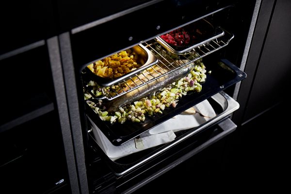 Forno con diverse teglie su più livelli contenenti cibo cucinato