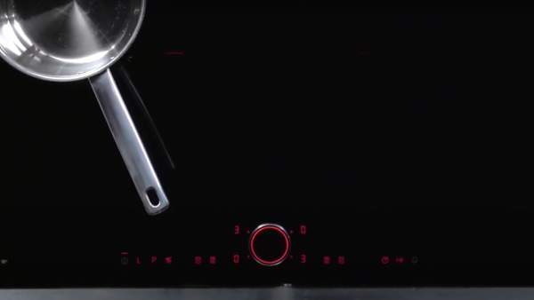 Pentola in acciaio inox sopra un piano cottura a induzione nero elegante con controlli touch illuminati sotto. 