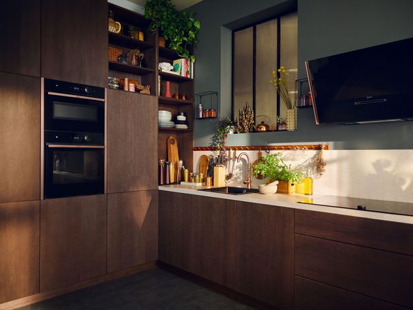 Braune Küche mit Elektrogeräten und Brushed Bronze Lisenen