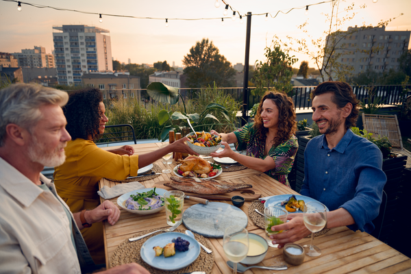 Tavolata di amici sorridenti che mangiano all’aperto
