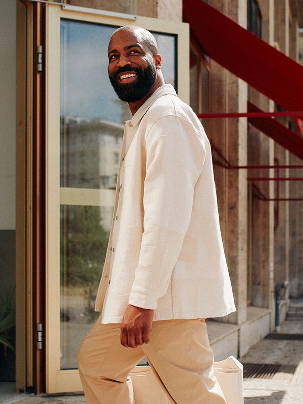 Lachende man met beige kleding loopt een gebouw binnen