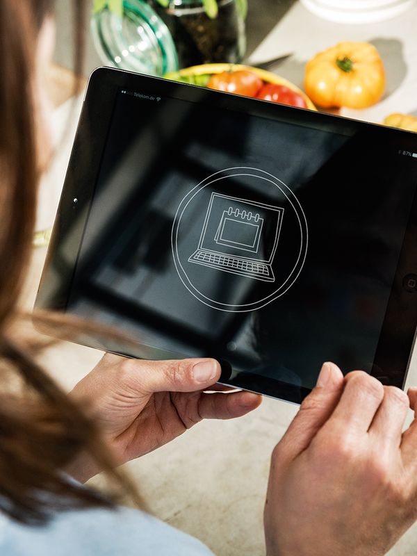 Vrouw gebruikt tablet waarop een icoon met een kalender te zien is