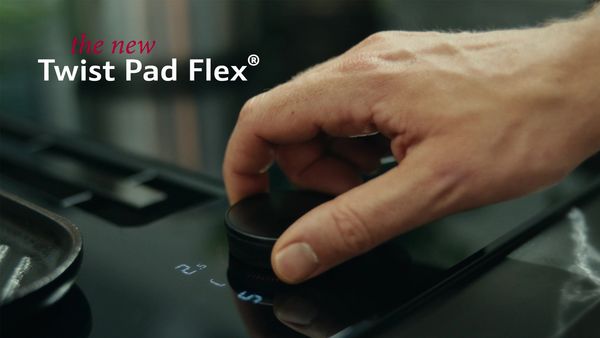 Käsi kääntämässä uutta Twist Pad Flex® -painiketta keittotasolla