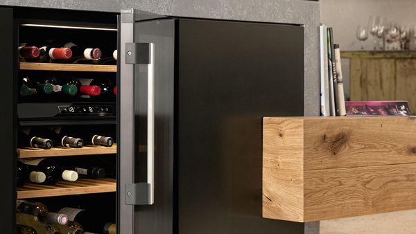 An open wine cooler with a full glass door and a long, sleek stainless steel handle