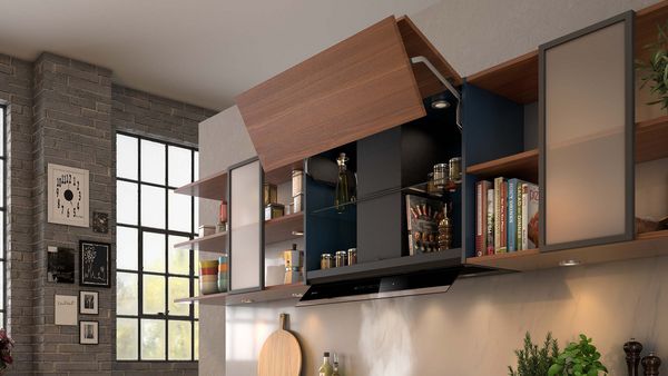 Cucina moderna dotata di ripiano in legno con ante in vetro, spezie, libri e un'elegante cappa nera sopra un piano di lavoro in marmo. Le grandi finestre forniscono luce.