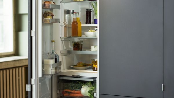 Un combiné réfrigérateur-congélateur encastrable ouvert à droite d'une grande fenêtre