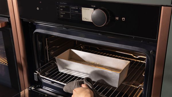 someone is putting a dish with the dough in a NEFF oven