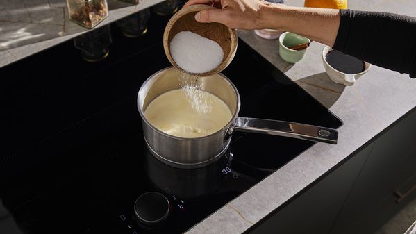 Adding sugar to the milk and heavy cream in the pot 