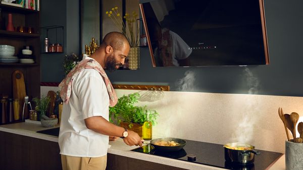En man förbereder mat i ett kök med NEFF vinklad takfläkt.