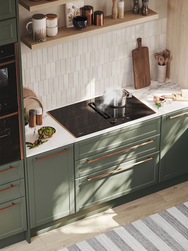 Šiuolaikinės alyvuogių žalumo spalvos virtuvės vaizdas su kaitlente su integruota ventiliacija, sumontuota po sieninėmis lentynomis