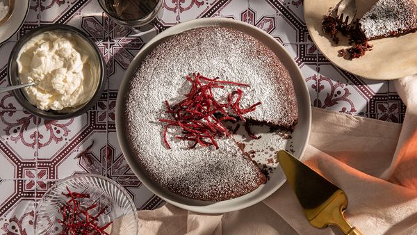 Beeld van een chocoladetaart met rode biet met een paar ingrediënten in kommetjes ernaast.  