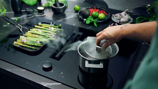 Kookplaat met afzuiging met daarop een pan en een grillpan.