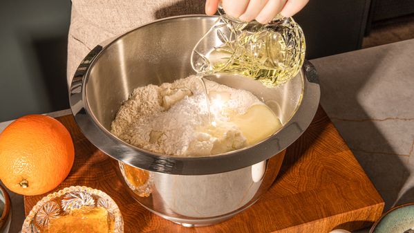 Adding oil into a bowl with flour