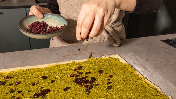 Sprinkling cranberrys over the dough and the pistachio filling