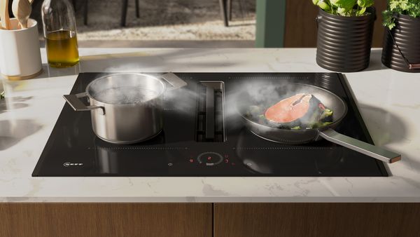  Beeld van een kookplaat met geïntegreerde afzuiging, die automatisch stoom van pannen wegzuigt.